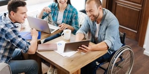 friends-gathered-around-table-wheelchair-support