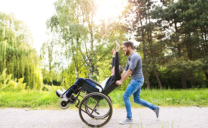 Person in wheelchair outside with assistance