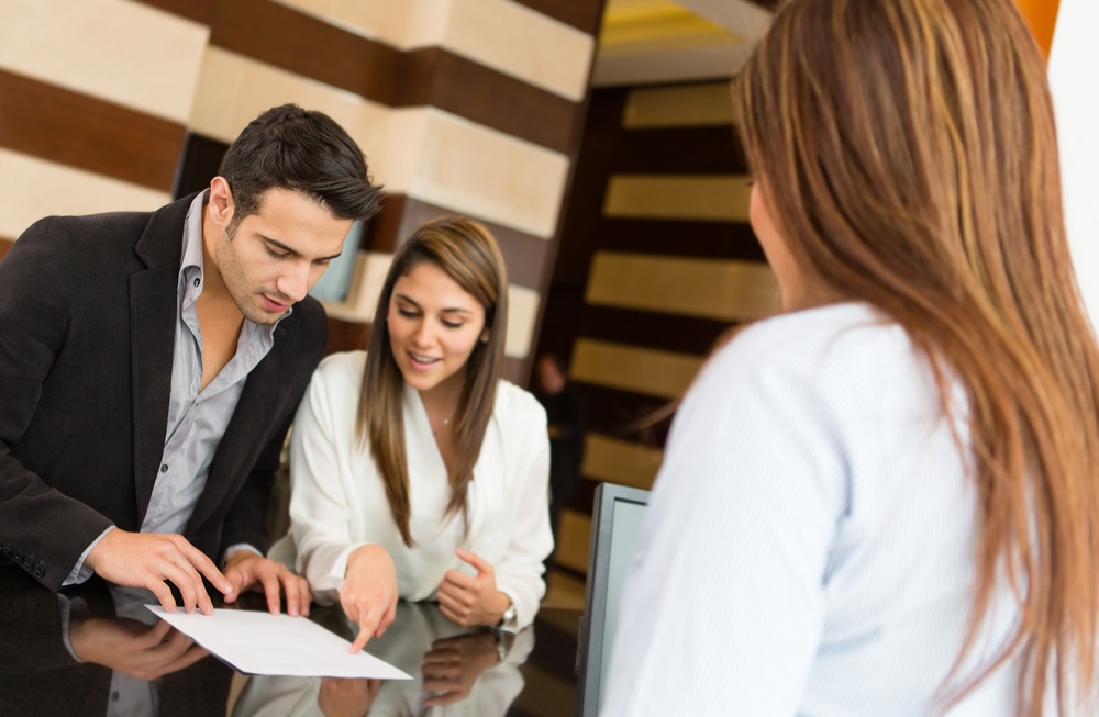 Couple checking in a hotel and talking to the receptionist