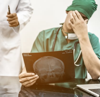stressed doctor covering face because of medical malpractice