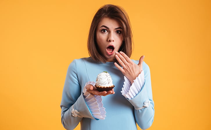 astonished young woman holding cake