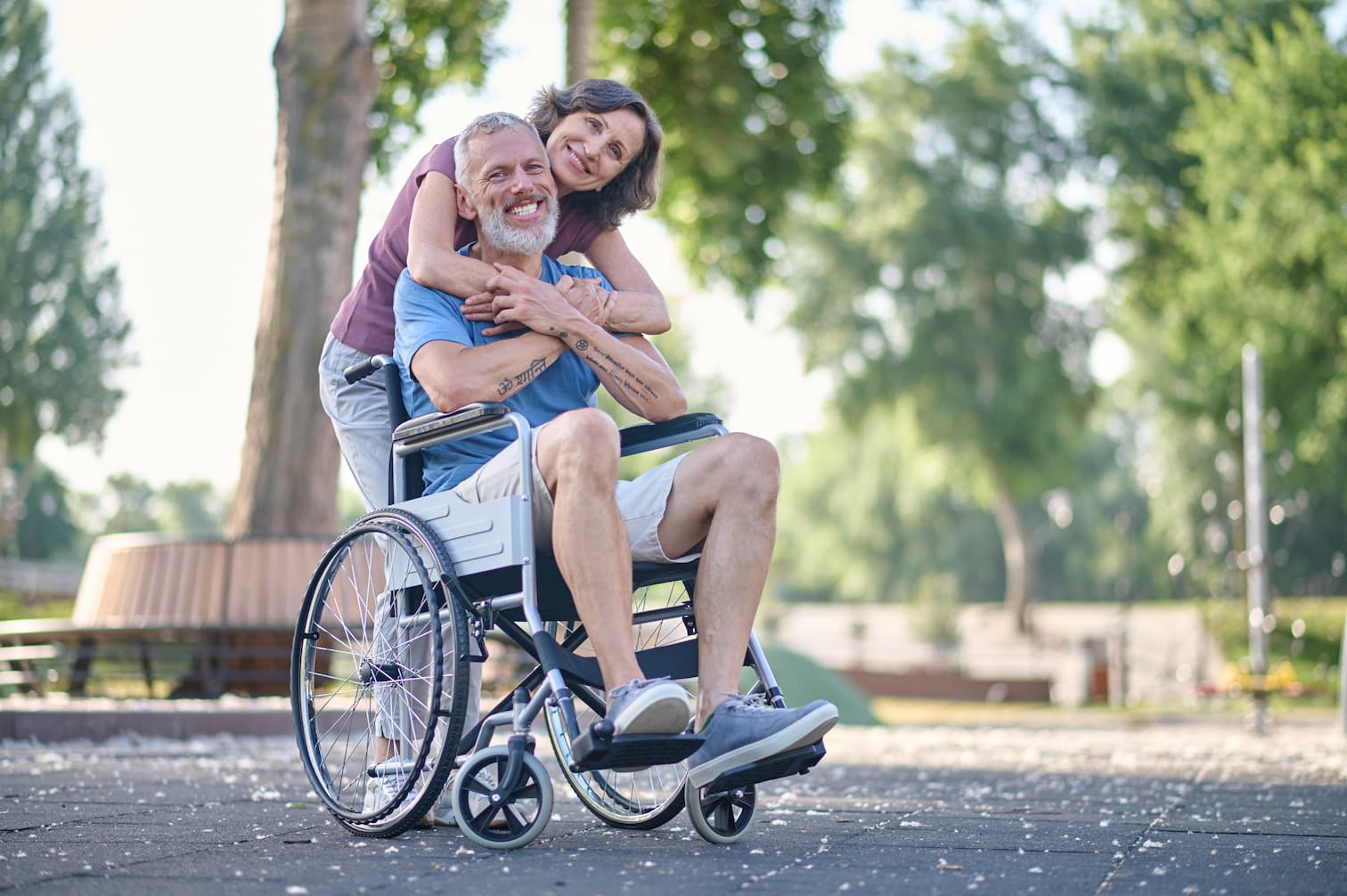 A woman hugging a man in a wheel chair smiling
